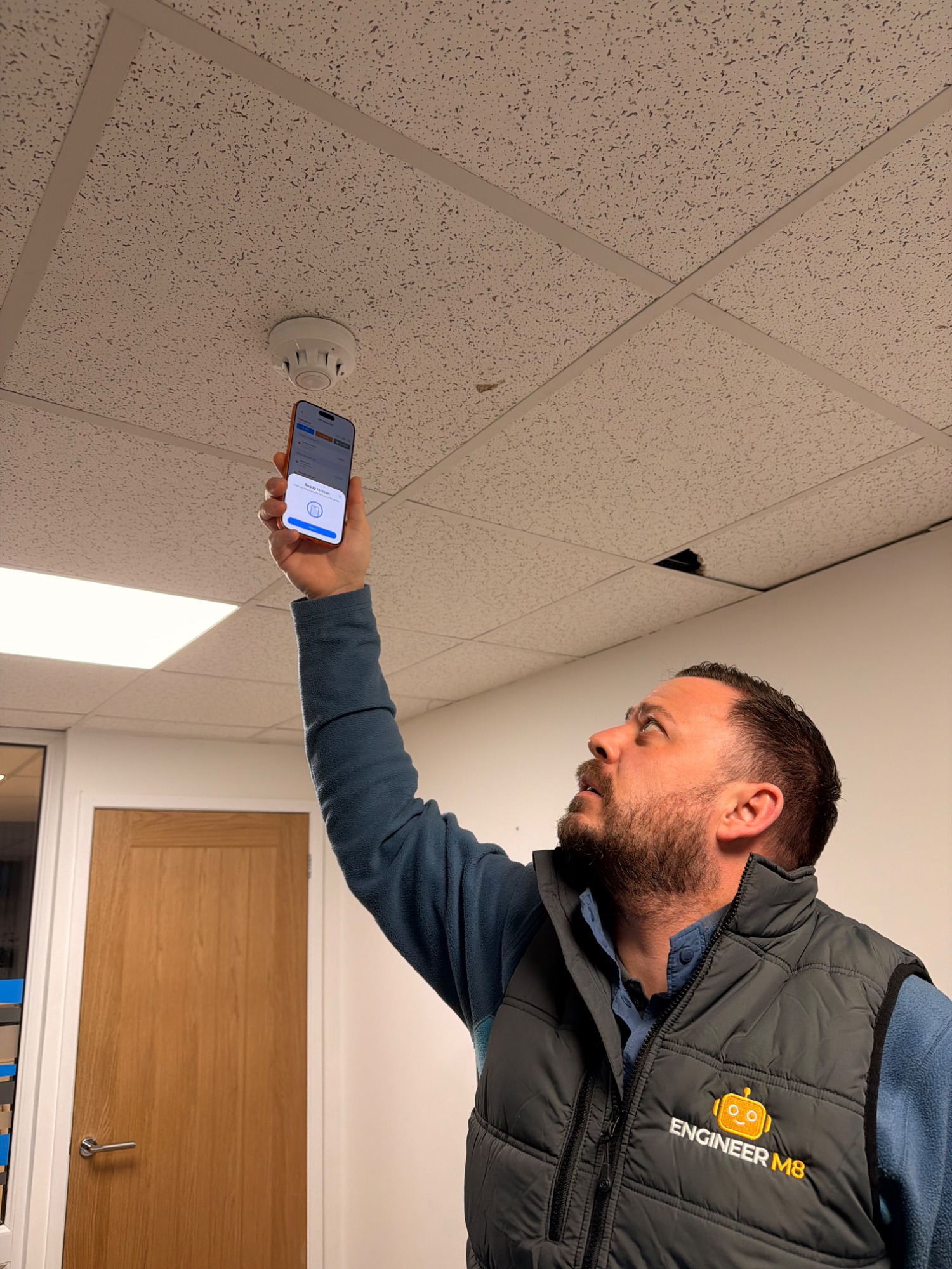 Engineer scanning fire detector with EM8HQ app and FireLog365